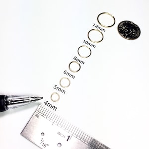 Six 14k gold filled endless hoops lined up in descending sizes from 12mm, 10mm, 8mm, 6mm, 5mm and 4mm laid out above ruler and next to dime.