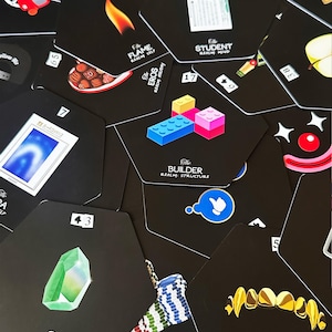 Può includere: Una collezione di carte esagonali nere con varie illustrazioni e testo. Le carte presentano immagini come una fiamma, mattoncini, una gemma e un simbolo di pollice in su. Ogni carta ha un numero e testo, come "The Builder Realm Structure."
