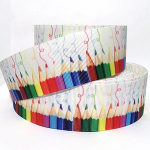 May include: White ribbon with a colorful pencil print. The pencils are arranged in a row and have different colors, including red, orange, yellow, green, blue, purple, and pink. The ribbon is perfect for adding a touch of whimsy to crafts, gifts, and home decor.