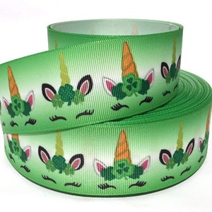 May include: Green and white ribbon with a repeating pattern of unicorn faces wearing shamrock wreaths. The unicorn horns are orange.