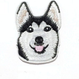 May include: Embroidered patch of a husky dog's face. The dog has black and white fur, a pink tongue sticking out, and a friendly expression.