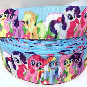 May include: A blue ribbon with a repeating pattern of My Little Pony characters. The ponies are pink, purple, yellow, blue, and white. The ribbon is perfect for crafting and decorating.