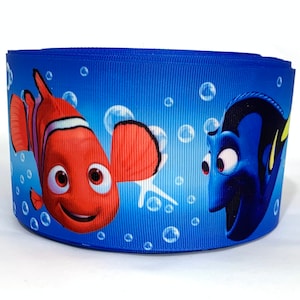 May include: A blue ribbon with a printed design of Nemo and Dory from the movie Finding Nemo. The ribbon features a blue background with white bubbles and the characters are in their signature colors.