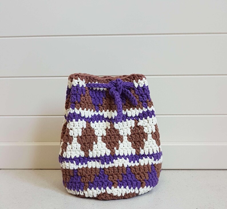 May include: A crocheted drawstring bag with a brown, white, and purple geometric pattern.