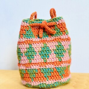 May include: A small, crocheted drawstring bag with a geometric pattern in shades of orange, pink, and green.