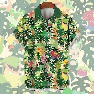 Peut inclure: Chemise à manches courtes avec col vert et imprimé intégral vibrant. Le motif présente divers personnages de dessins animés et de grandes feuilles vertes sur un fond jaune clair. La chemise est suspendue à un cintre en bois.