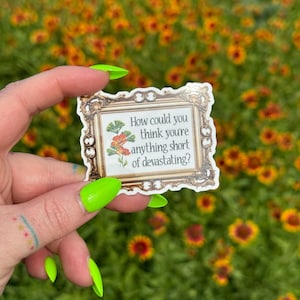 Könnte beinhalten: Ein Aufkleber mit einem dekorativen Goldrahmen und dem Text "How could you think you're anything short of devastating?" Der Aufkleber zeigt auch eine florale Illustration. Der Hintergrund ist ein Feld aus orangefarbenen und gelben Blumen.