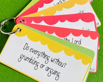 May include: A set of colorful cards with inspirational quotes and bible verses. The cards are attached to a silver ring and feature scalloped edges. The text on the front card reads "Do everything without grumbling or arguing. Philippians 2:14".