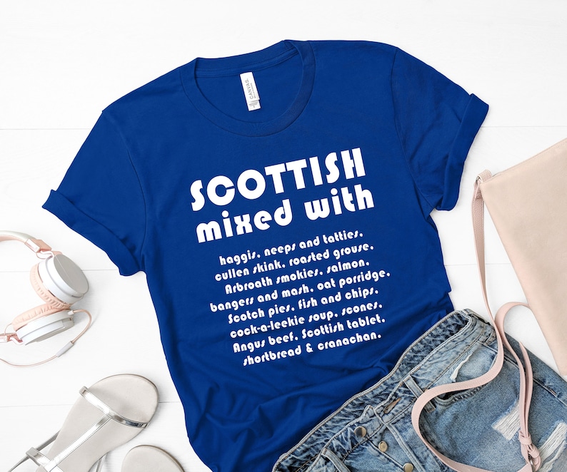 Może przedstawiać: Koszulka w kolorze kr&oacute;lewskiego błękitu z białym napisem "SCOTTISH mixed with" i listą r&oacute;żnych szkockich potraw i napoj&oacute;w.