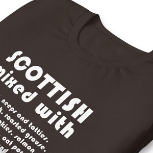 Może przedstawiać: Ciemnobrązowy t-shirt z białym napisem "SCOTTISH mixed with neeps and tatties, roasted grouse, akies, salmon, oat por, and"