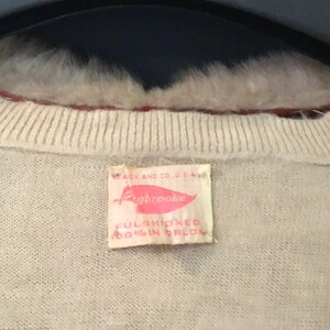 May include: A white sweater with a pink and white label that reads "Aybrooke, Full Fashioned 100% Orlon".