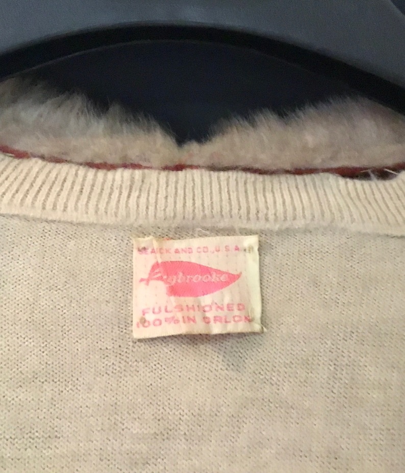 May include: A white sweater with a pink and white label that reads "Aybrooke, Full Fashioned 100% Orlon".