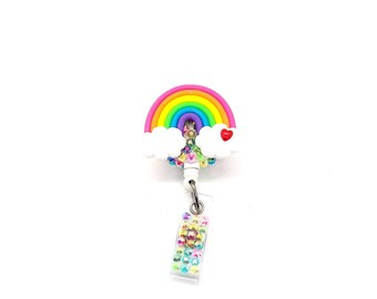 May include: A rainbow-colored badge reel with a white cloud and a red heart. The reel has a clear plastic badge holder with colorful rhinestones.