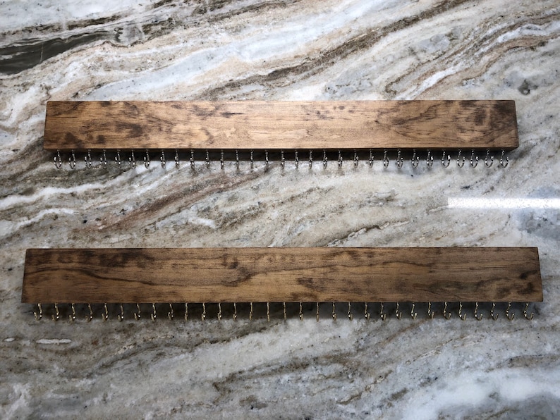 Puede incluir: Dos organizadores de joyas de madera con ganchos de metal. Cada organizador tiene un acabado te&ntilde;ido de color marr&oacute;n oscuro y mide aproximadamente 40 cm de largo.