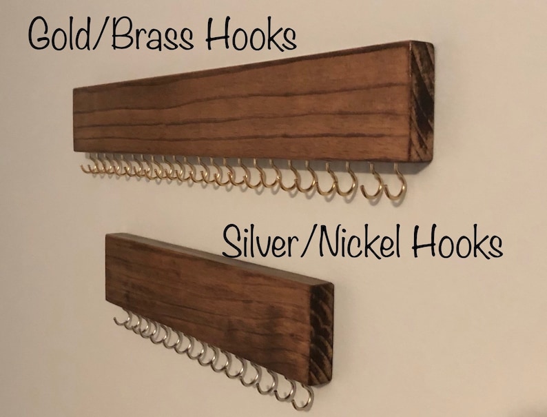 Puede incluir: Dos organizadores de joyas de pared de madera con ganchos. El organizador superior tiene ganchos dorados y el organizador inferior tiene ganchos plateados. El texto "Gold/Brass Hooks" est&aacute; sobre el organizador superior y el texto "Silver/Nickel Hooks" est&aacute; sobre el organizador inferior.