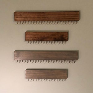 Puede incluir: Cuatro organizadores de joyas de pared de madera con ganchos de metal. Los dos organizadores superiores est&aacute;n te&ntilde;idos de un color marr&oacute;n oscuro. Los dos organizadores inferiores est&aacute;n te&ntilde;idos de un color gris claro.