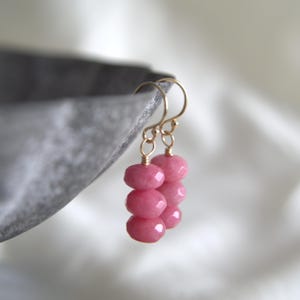 Peut inclure: Boucles d'oreilles en pierres précieuses roses avec du fil d'or enroulé autour de chaque pierre. Les boucles d'oreilles sont composées de trois pierres précieuses roses sur chaque boucle d'oreille.