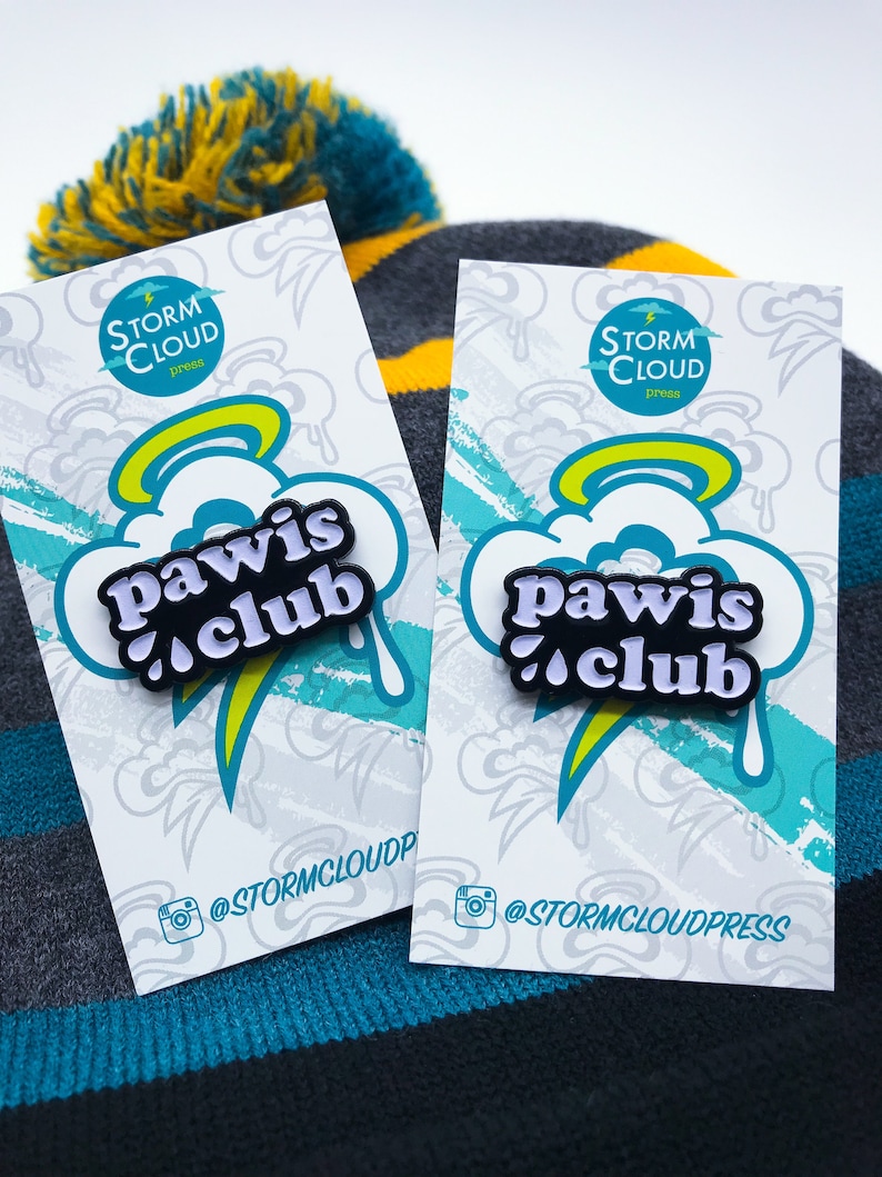 Peut inclure: Deux cartes blanches avec un motif bleu et jaune repr&eacute;sentant une &eacute;pingle en &eacute;mail noir et blanc avec le texte "Pawis Club" sur un nuage blanc avec une aur&eacute;ole jaune. Les cartes portent le texte "Storm Cloud Press" et le nom d'utilisateur Instagram "@stormcloudpress".
