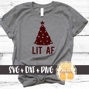 以下が含まれることがあります： 赤いクリスマスツリーのデザインと「LIT AF」の文字が書かれた灰色のTシャツ。Tシャツは下で結ばれています。「SVG + DXF + PNG」という文字が画像の左下に表示されています。「CHEESE TOAST digitals」という文字のロゴが画像の右下に表示されています。