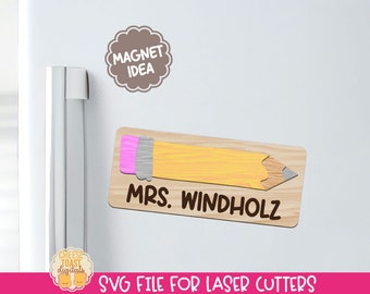 May include: A wooden pencil-shaped magnet with the text "MRS. WINDHOLZ" on it. The magnet is on a white refrigerator door. The text "MAGNET IDEA" is on a brown cloud-shaped sticker above the magnet.