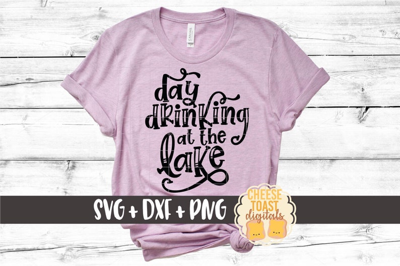 May include: A pink t-shirt with the text "day drinking at the lake" in black. The shirt is on a white wood background. The text "SVG + DXF + PNG" is below the design. The text "CHEESE TOAST digitals" is in a yellow circle with a black outline.