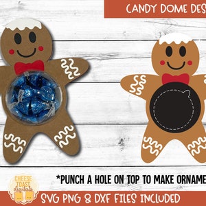 May include: Gingerbread man-shaped candy holders. One holds blue candies in a clear dome, the other has a black circle. Both have white icing details, red bow ties, and the text "CANDY DOME DESIGN". The text "PUNCH A HOLE ON TOP TO MAKE ORNAMENTS!" is also visible.
