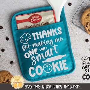 May include: A turquoise blue oven mitt with the text "THANKS for making me ONE smart COOKIE" in white. The oven mitt has a pocket on the top with a Betty Crocker chocolate chip cookie mix bag inside.
