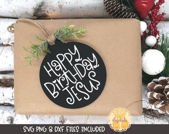 May include: A black circle ornament with white text that reads "Happy Birthday Jesus". The ornament is hanging from a brown paper bag with a green sprig of greenery.