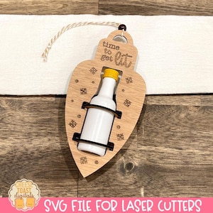 May include: A wooden lightbulb ornament with a small bottle inside. The ornament is decorated with snowflakes and the text "time to get lit".