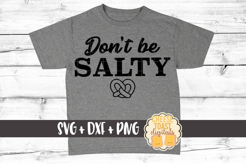 Pu&ograve; includere: Maglietta grigia con il testo "Don't be SALTY" in lettere nere. Un pretzel si trova sotto il testo. Il testo "SVG + DXF + PNG" &egrave; in fondo alla maglietta. Un logo per "Cheese Toast Digitals" si trova in basso a destra.