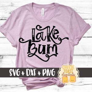 May include: A pink t-shirt with the text "Lake Bum" in black lettering. The shirt is on a white wood background. The text "SVG + DXF + PNG" is in the lower left corner of the image. The text "CHEESE TOAST digitals" is in the lower right corner of the image.