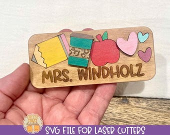 May include: Wooden name tag with the text "MRS. WINDHOLZ" and a pencil, coffee cup, apple, and hearts.