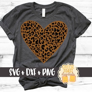 May include: A gray t-shirt with a brown and black leopard print heart design. The text "SVG + DXF + PNG" and "CHEESE TOAST digitals" is printed on the shirt.