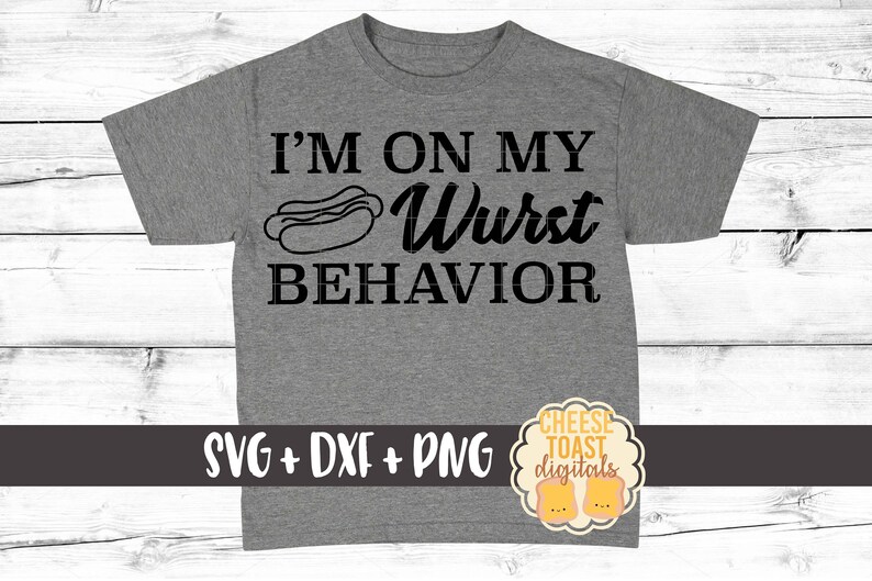 Pu&ograve; includere: Una maglietta grigia con il testo "I'm on my Wurst Behavior" e un cartone animato di un hot dog. Il testo "SVG + DXF + PNG" &egrave; nella parte inferiore della maglietta. Un logo per "Cheese Toast Digitals" &egrave; nell'angolo in basso a destra.