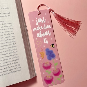 May include: Pink bookmark with a floral design and a bee. The bookmark has the text "just make dua about it" in white lettering.