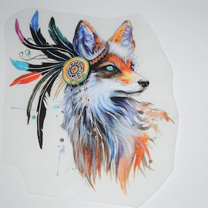 Pode incluir: Ilustração em aquarela de uma raposa com olhos azuis, adornada com um cocar de penas. A raposa apresenta pelagem laranja, branca e marrom, com respingos azuis e roxos. O cocar inclui penas pretas, azuis, vermelhas e turquesas.