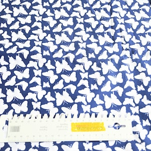 Könnte beinhalten: Weiße Schmetterlings-Silhouetten auf einem dunkelblauen Stoff. Der Stoff wird mit einem Lineal zur Skalierung gezeigt.