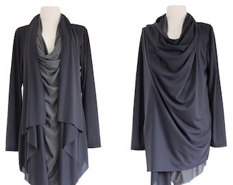 May include: Two dark gray draped tops displayed on wooden dress forms. The tops have long sleeves and asymmetrical hemlines. One has a layered design, while the other features a cowl neck. The dress forms are on a white background.