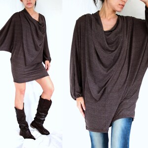 May include: A brown, long-sleeved, draped tunic top with a cowl neck. The top is made of a soft, stretchy fabric and has a relaxed fit.