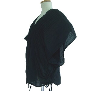 May include: A black, loose-fitting, short-sleeved top with a V-neck and a drawstring at the bottom.