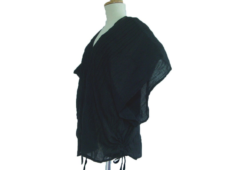May include: A black, loose-fitting, short-sleeved top with a V-neck and a drawstring at the bottom.