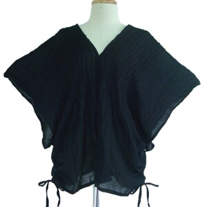 May include: A black, loose-fitting, short-sleeved top with a V-neck and a drawstring at the bottom.