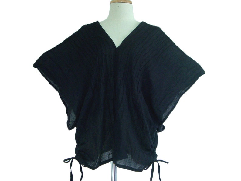 May include: A black, loose-fitting, short-sleeved top with a V-neck and a drawstring at the bottom.