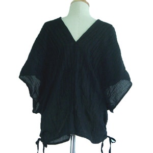 May include: A black, loose-fitting, short-sleeved top with a V-neck and a gathered detail at the bottom.