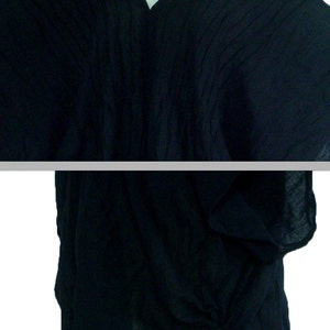 May include: A black, loose-fitting, short-sleeved top with a V-neck and a drawstring at the bottom.