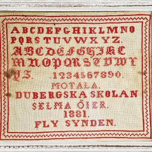 May include: A framed sampler with red embroidery on a white linen background. The sampler includes the alphabet, numbers, the word "Motala", the text "Dubergska skolan", "Selma Oier", "1881", and "Fly Synden."