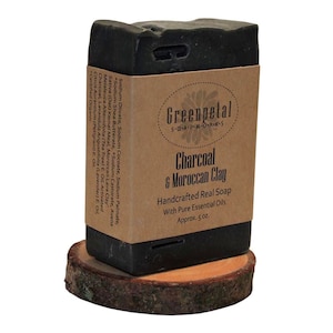 May include: A black bar of soap with a brown label that reads "Greenpetal Soapworks" and "Charcoal & Moroccan Clay Handcrafted Real Soap with Pure Essential Oils Approx. 5 oz."