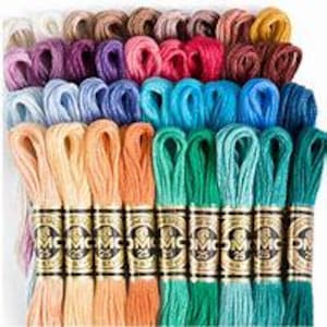 May include: A selection of embroidery floss skeins in a range of colours, such as pink, blue, green, orange, and brown. Each skein is labelled with a brand name and number. The floss is neatly arranged, displaying a spectrum of shades.