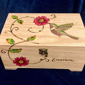 May include: A wooden box featuring a hummingbird and floral design. The box has a hinged lid with a brass latch and is personalised with the name "Emerson".