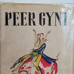 Puede incluir: Una cubierta de libro vintage con el título "Peer Gynt" de Henrik Ibsen. La cubierta presenta una ilustración colorida de dos figuras montando un cerdo.
